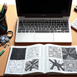 **A graphic designer's desk littered with tools, both digital and physical. Open source graphics editor on a computer screen. Sketchbooks, pencils, and swatches scattered around. Focus on the creative chaos and the blend of traditional and modern design techniques.**